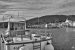 Photographie en noir et blanc d'un bateau amarré à Cadaqués, avec le village en fond.