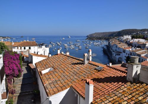 Panorama sur les façades, les toits et le port de Cadaqués avec ses nombreux bateaux.