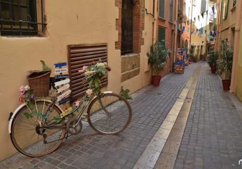 Charmante ruelle de Collioure avec des fanions colorés et un vélo décoratif.