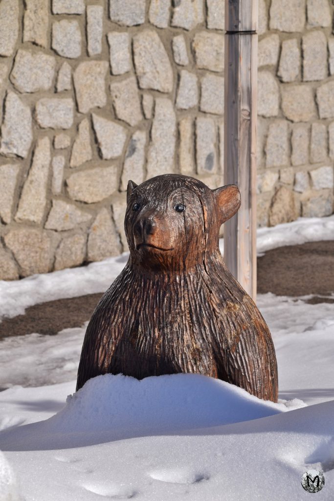 Sculpture d'ourson en bois dans la neige
