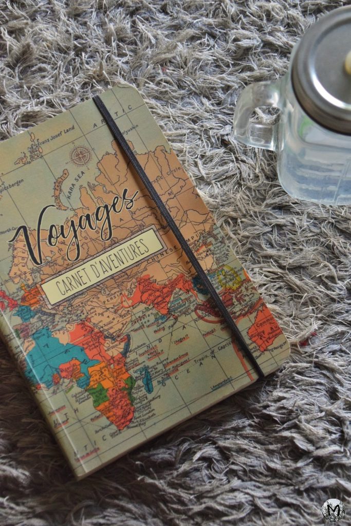 Un carnet de voyages posé sur un tapis