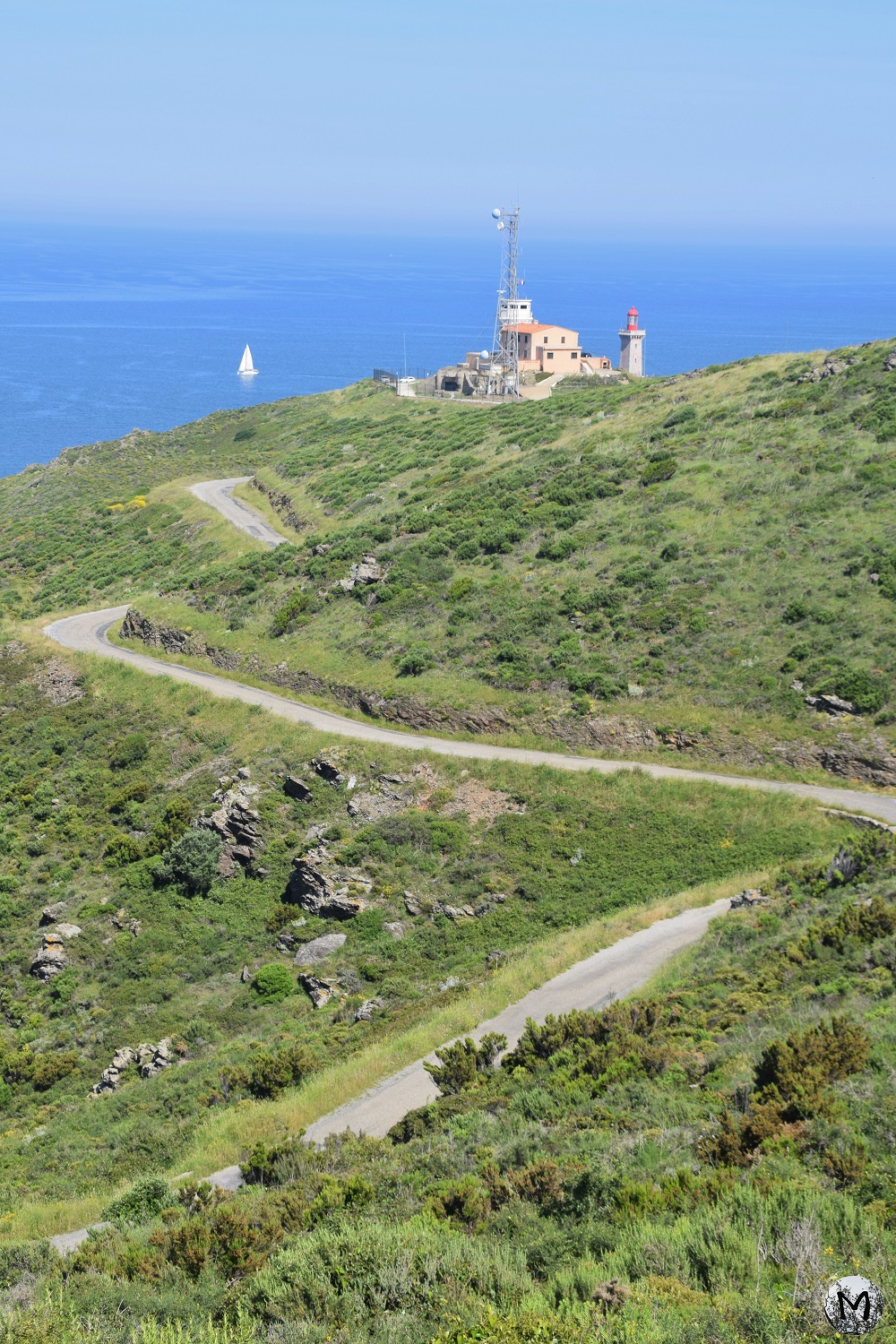 Petite route goudronnée menant au phare du Cap Béar avec vue sur la mer Méditerranée.