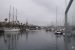 Le port Vell à Barcelone sous le ciel gris avec les mâts des bateaux se reflétant dans l'eau.